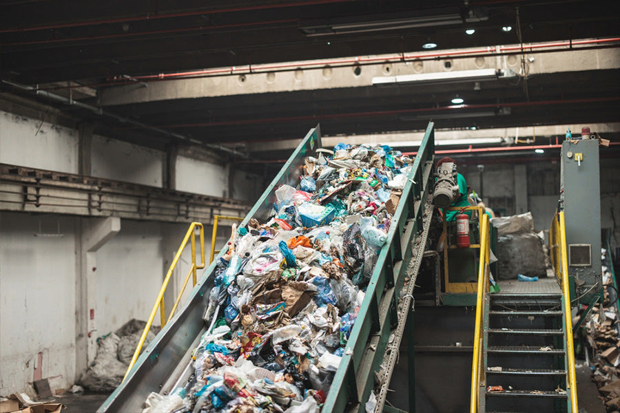 Industrial waste sorting conveyor in recycling facility, managing mixed plastic and paper waste